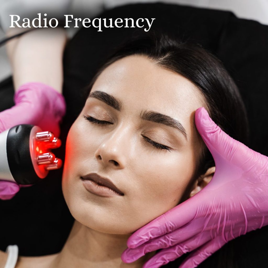 Woman with her eyes closed lying down and her head visible. Another person is doing a radio frequency treatment, with one hand on her face and the other holding a radio frequency device.