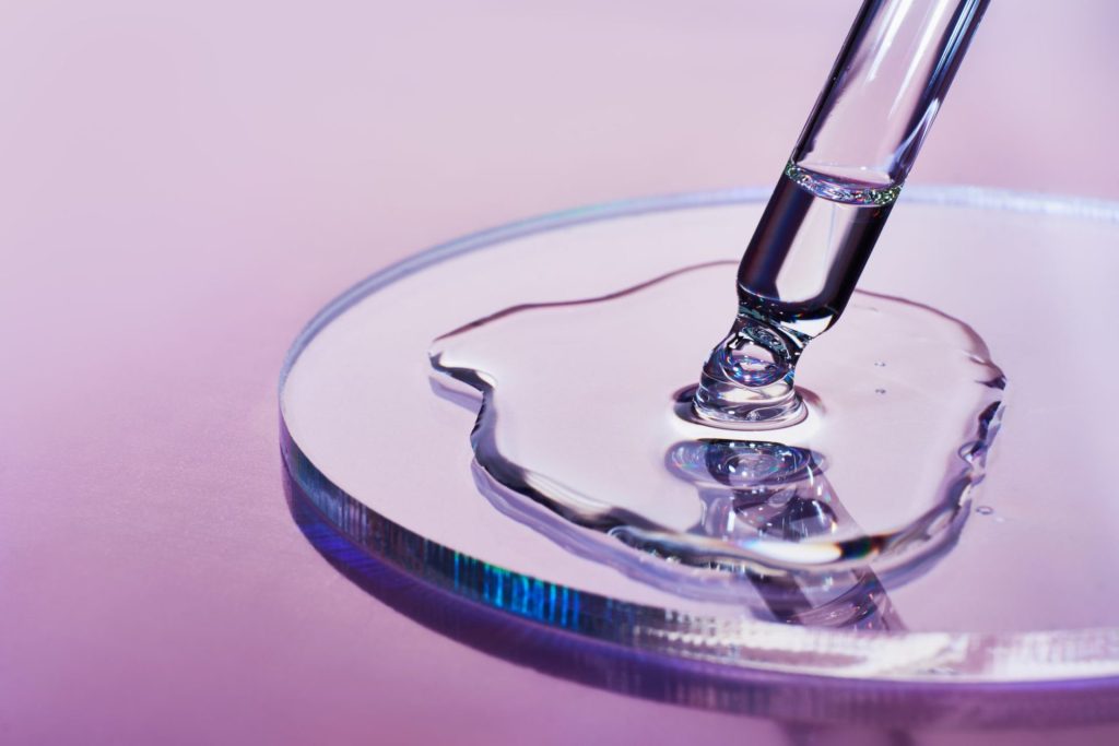Close-up of a laboratory pipette dispensing liquid sample into a petri dish for scientific testing and quality control in food manufacturing and processing.