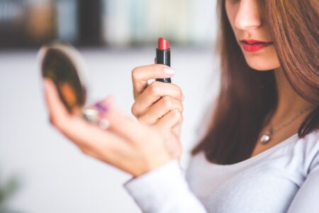 Woman holding lipstick and a compact mirror