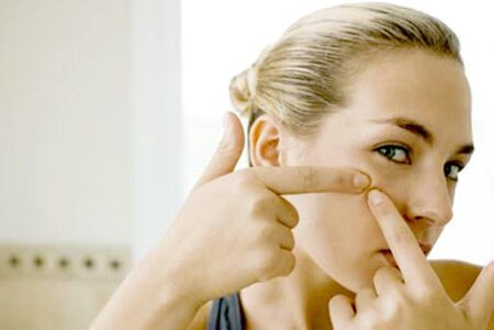 Woman squeezing pimple on cheek