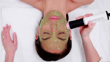 Woman receiving professional spa facial mask treatment with applicator brush during beauty skincare session.